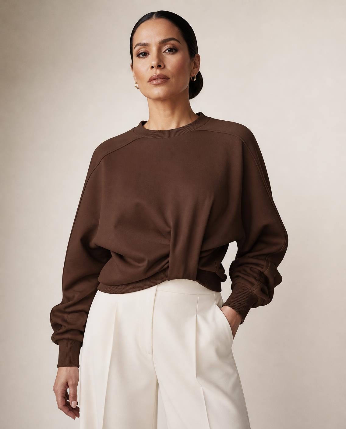 Model wearing the Stockholm twist front sweatshirt in chocolate brown with ivory wide-leg trousers, a Toronto fall fashion 2026 look