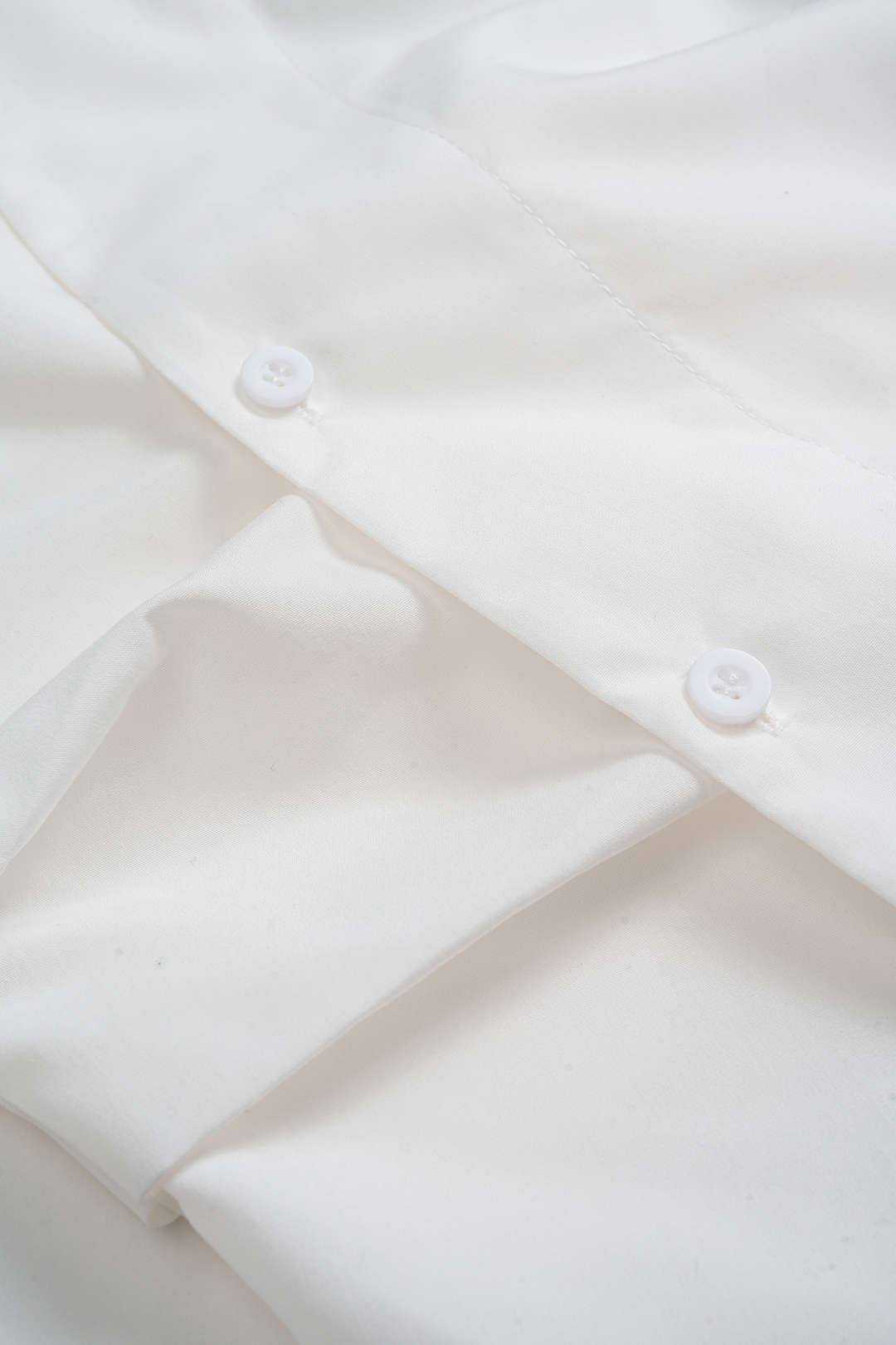 Close-up of the white shirting and buttons on the Lisbon Wrap Top