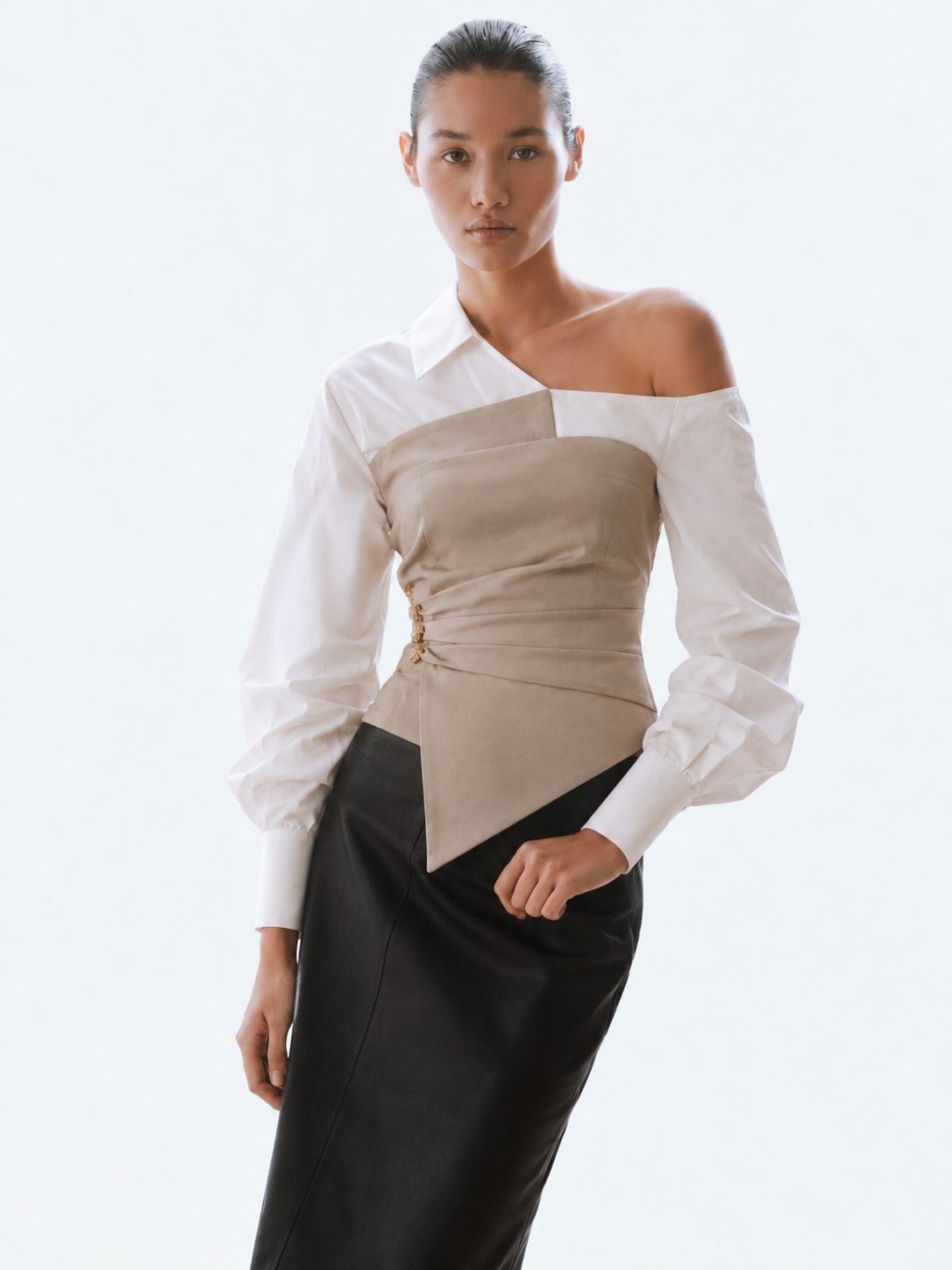 Model wearing the Milan Beige Top, a one shoulder white shirt with beige corset, styled with a black leather skirt