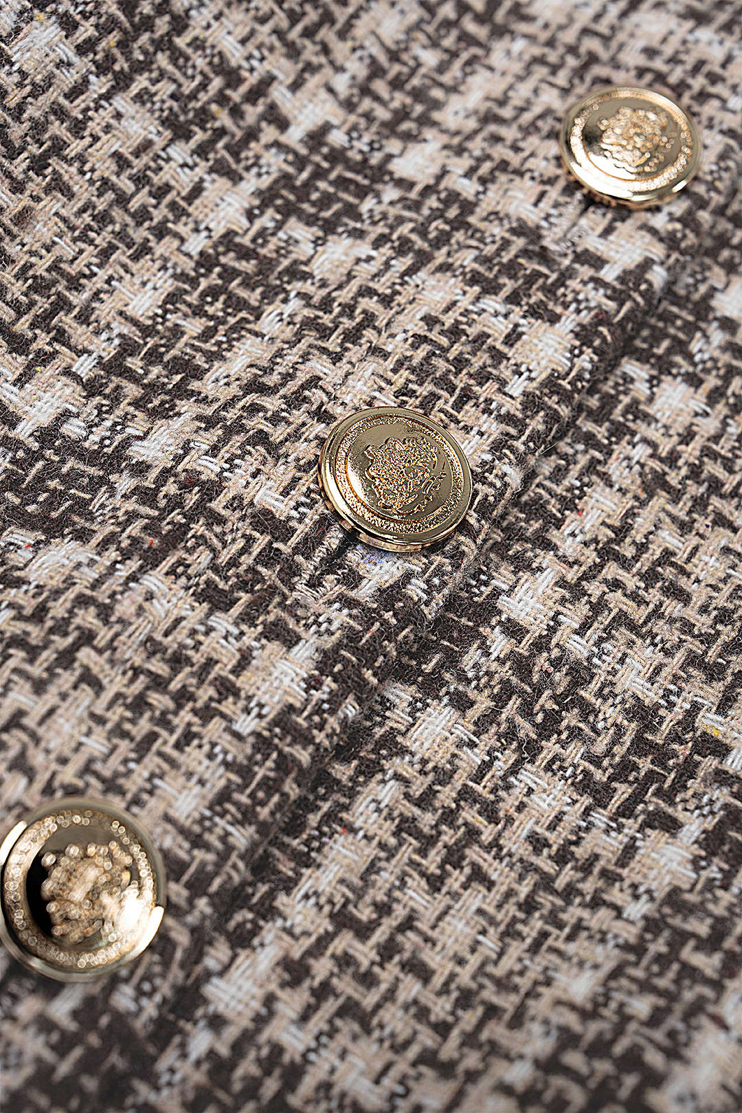 Detail of the Monaco Tweed Top: gold-tone button on woven tweed